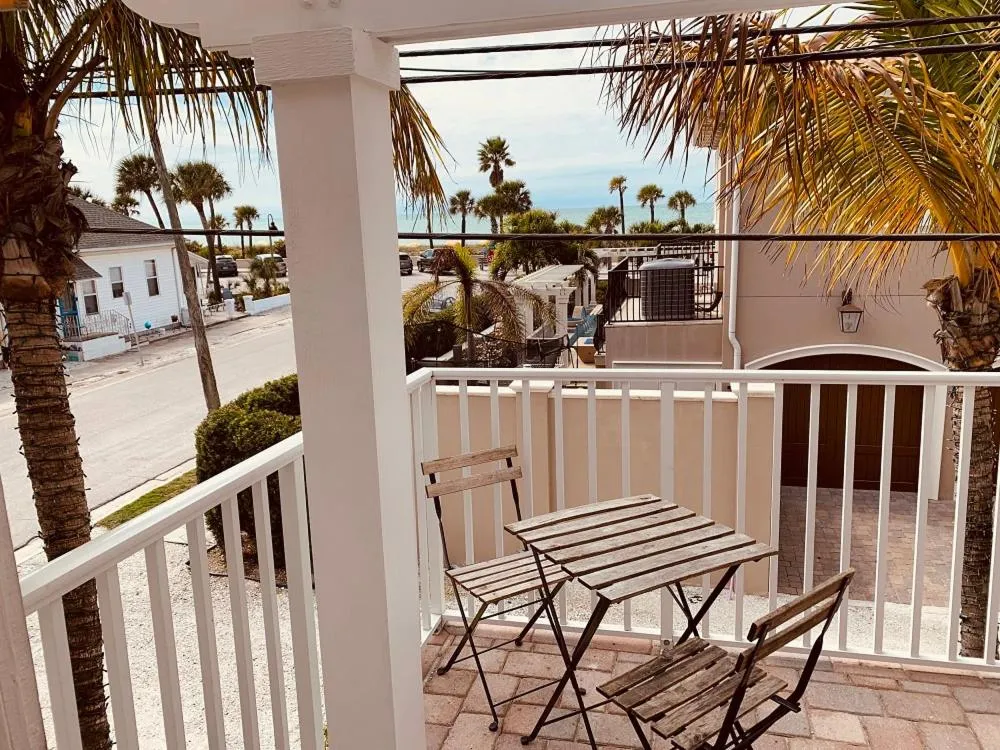 Une terrasse avec une table et des chaises offre une vue sur la mer et la végétation.