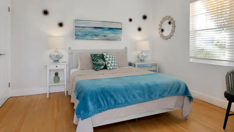 Une chambre lumineuse avec un grand lit recouvert d'une couverture turquoise.