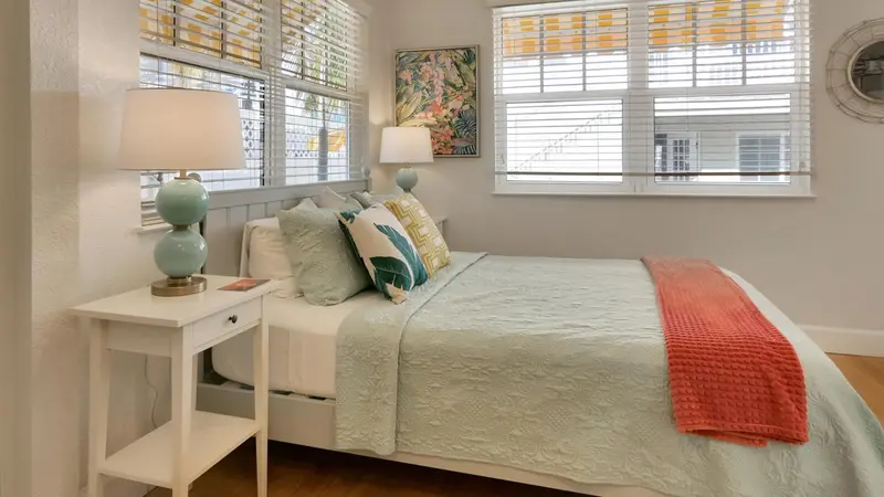 Une chambre lumineuse avec un lit recouvert de coussins et d'une couverture.
