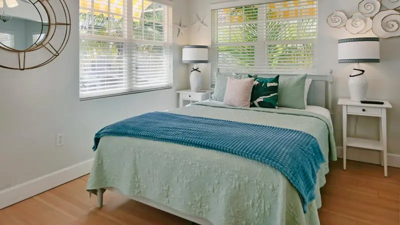 Une chambre lumineuse avec un lit recouvert d'une couverture bleue et de coussins.