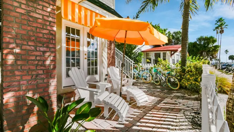 Terrasse avec mobilier blanc et store orange devant un bâtiment en briques.