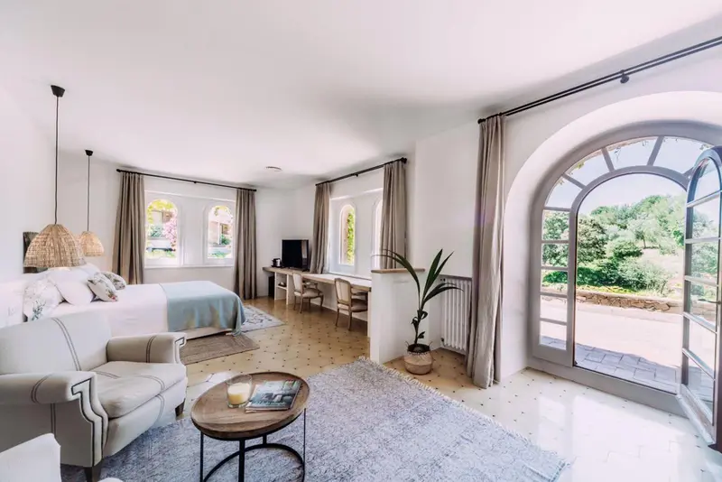 Une chambre lumineuse avec un coin salon et un accès à une terrasse.