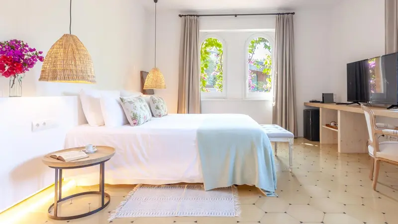 Chambre lumineuse avec un lit recouvert de textiles blancs et bleus.