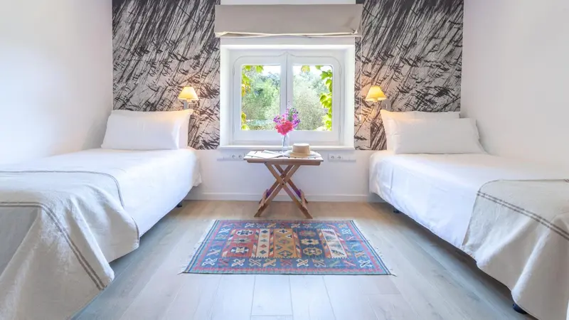 Une chambre lumineuse avec deux lits simples et une décoration colorée.