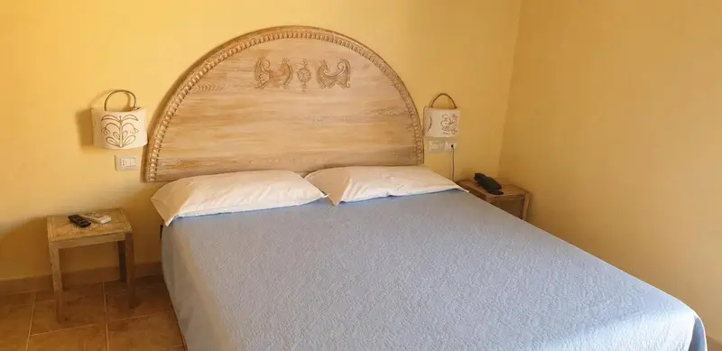 Une chambre lumineuse avec un grand lit et une tête de lit sculptée.