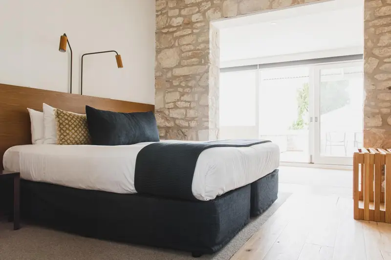 Une chambre lumineuse avec un grand lit recouvert d'une couverture sombre.