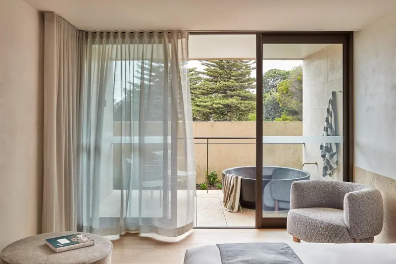 Une chambre lumineuse s'ouvre sur une terrasse avec baignoire.
