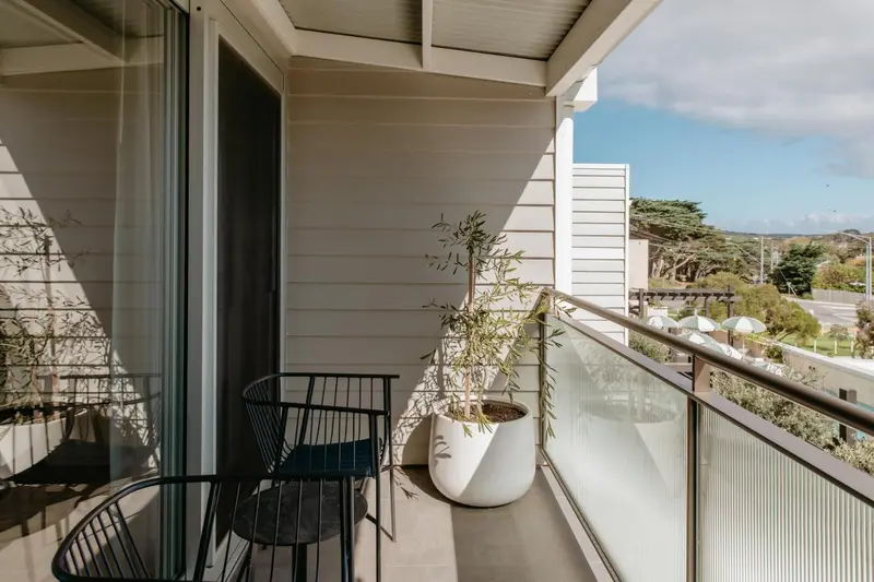 Terrasse avec mobilier en métal et plante en pot offrant une vue sur un paysage côtier.