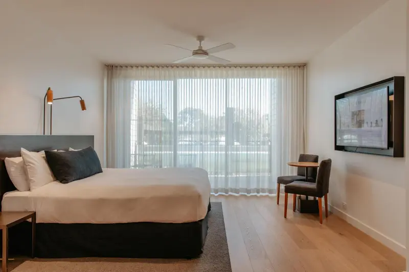 Une chambre lumineuse avec un grand lit et une vue sur la ville.