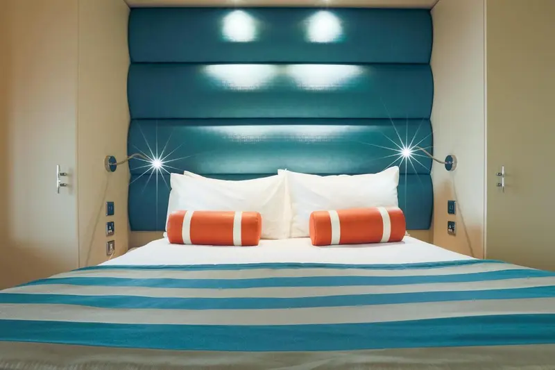 Un lit double avec oreillers et coussins colorés dans une chambre.