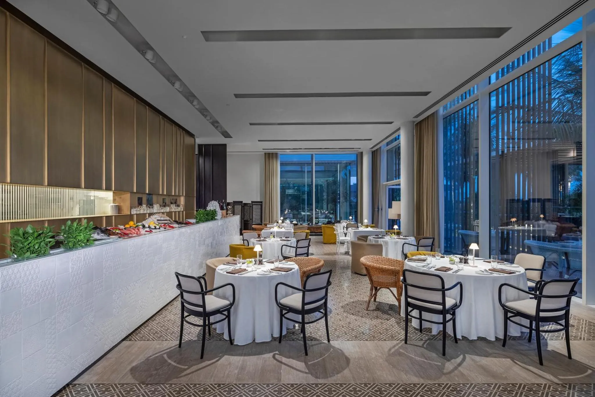 Une salle de restaurant lumineuse avec des tables dressées et un buffet.