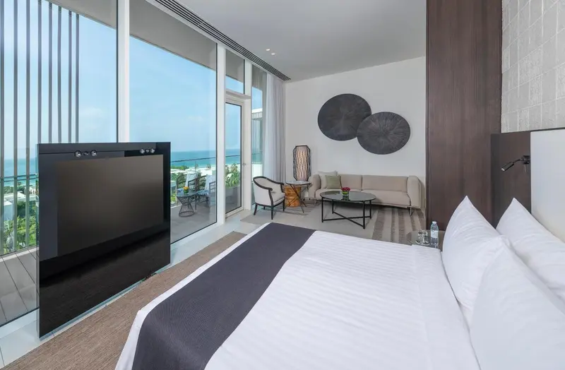 Une chambre lumineuse avec un grand lit et un accès à un balcon offrant une vue sur la mer.