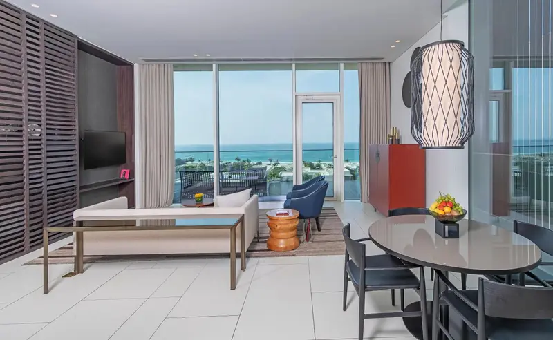 Espace de vie lumineux avec canapé, table basse et vue sur la mer.