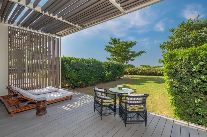 Terrasse aménagée avec chaises et transats donnant sur un jardin verdoyant.