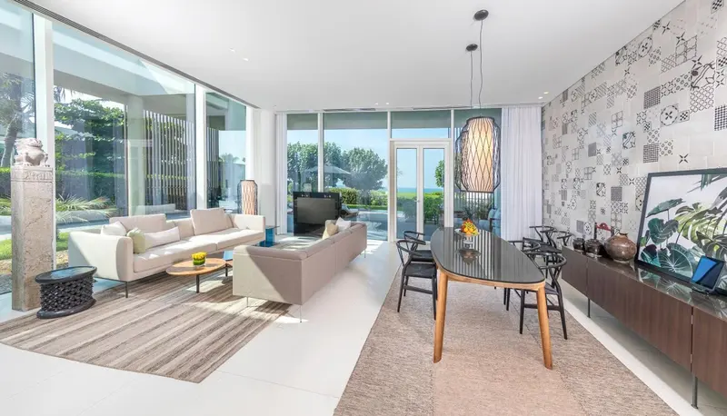 Espace de vie lumineux avec canapés, table à manger et vue sur l'extérieur.
