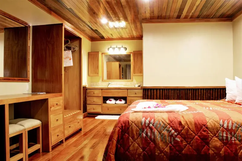 Une chambre lumineuse avec un lit recouvert d'une courtepointe colorée et un espace bureau en bois.