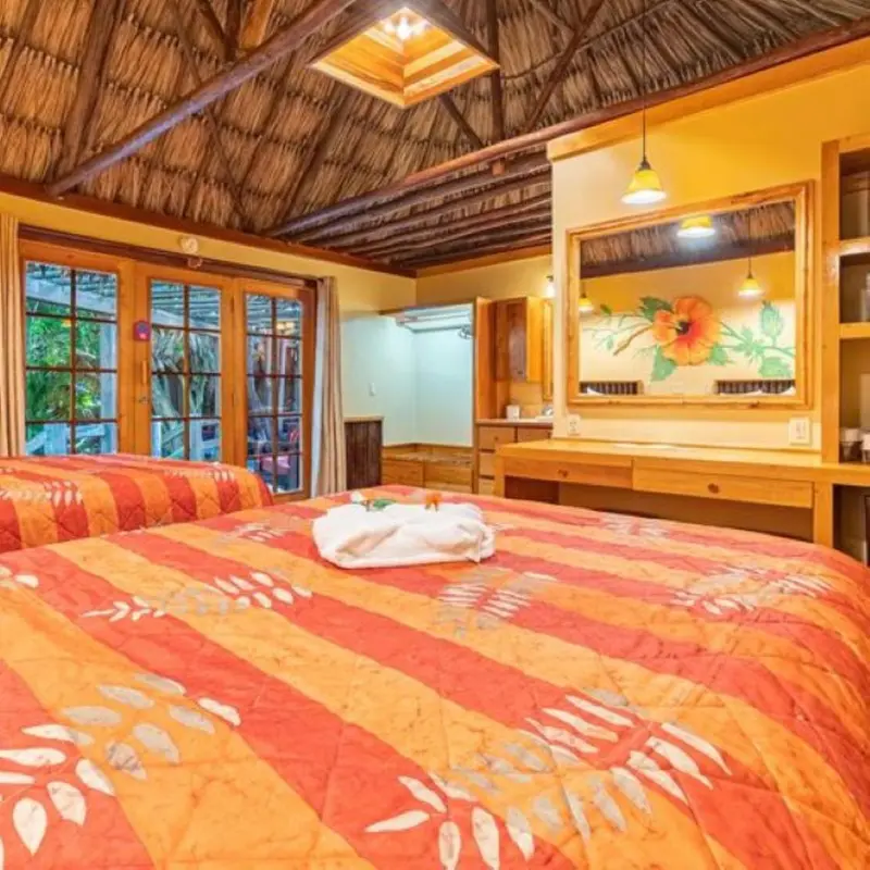 Une chambre lumineuse avec un lit recouvert d'une courtepointe colorée et un bureau en bois.