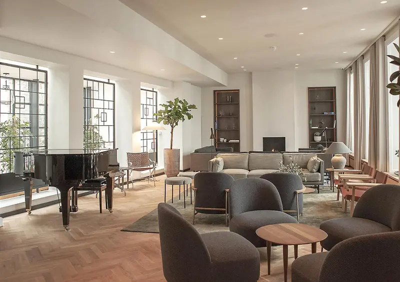 Un espace de détente intérieur avec un piano à queue et des fauteuils.