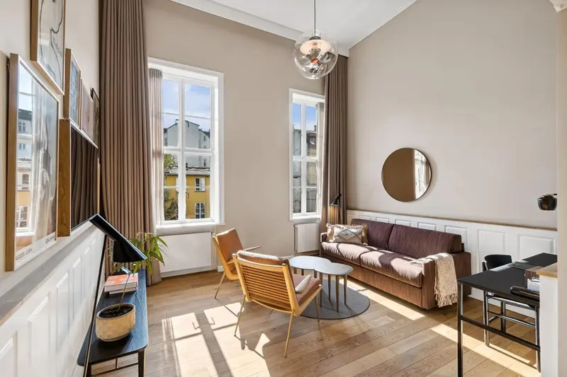 Un salon lumineux avec canapé, fauteuil et bureau près d'une fenêtre.