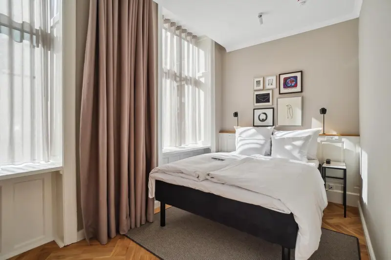 Une chambre lumineuse avec un lit double et des rideaux.