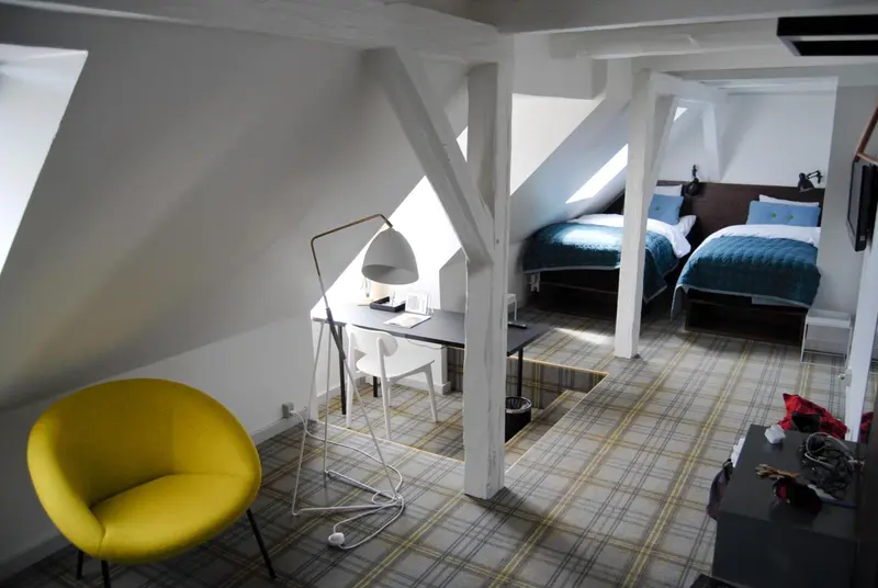 Une chambre mansardée avec un bureau et un fauteuil jaune.