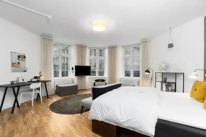 Une chambre lumineuse avec un grand lit et un espace bureau.