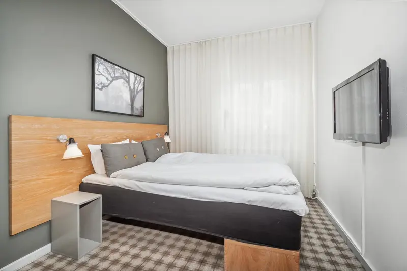 Une chambre lumineuse avec un grand lit et une décoration sobre.