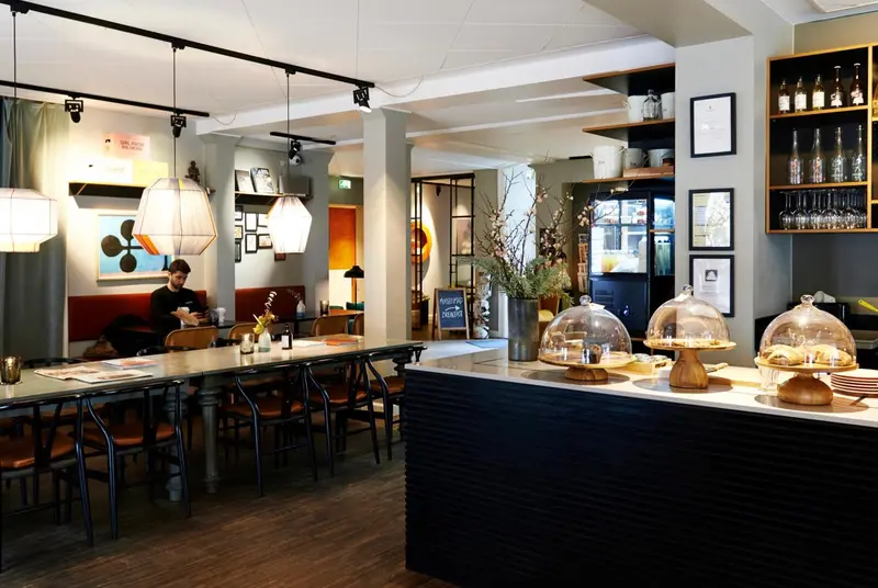 Une salle lumineuse avec des tables, des chaises et un comptoir de présentation de pâtisseries.
