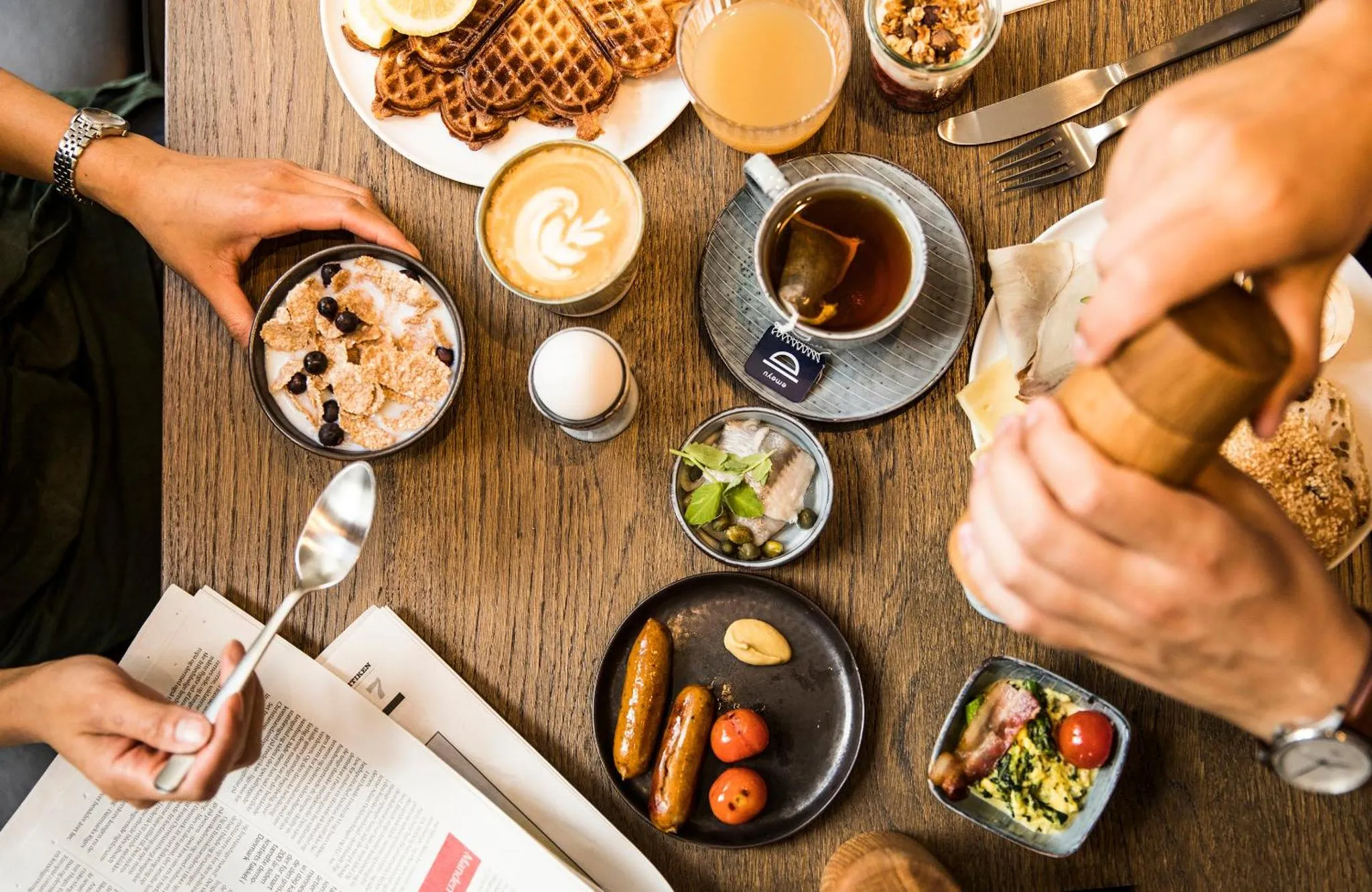 Une table en bois présente un petit-déjeuner copieux avec des boissons, des pâtisseries et des accompagnements.
