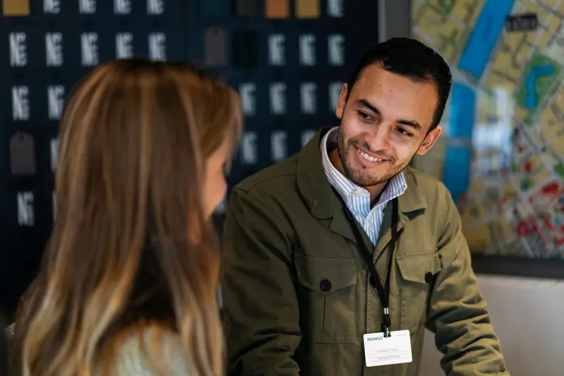 Un homme souriant regarde vers la caméra dans un intérieur clair.