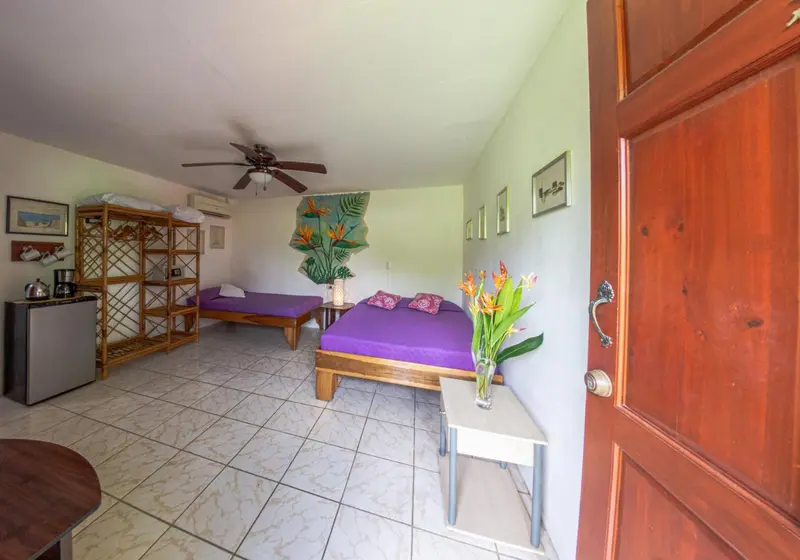 Une chambre lumineuse avec un lit violet et une décoration florale.