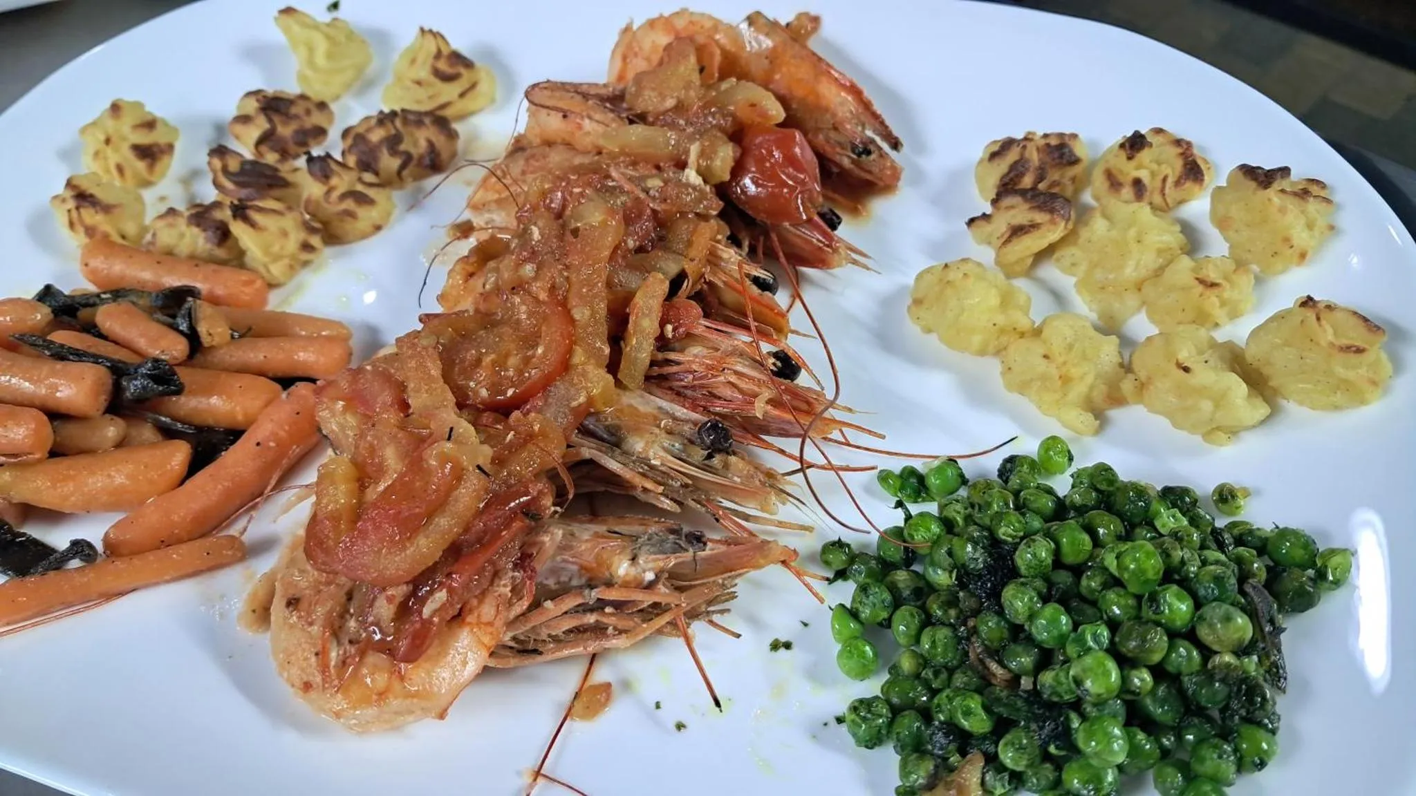 Assiette de crevettes grillées accompagnées de légumes et de pommes de terre.