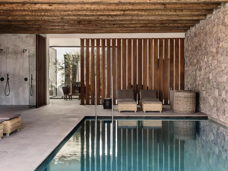 Une piscine intérieure avec des chaises longues et un mur en bois.