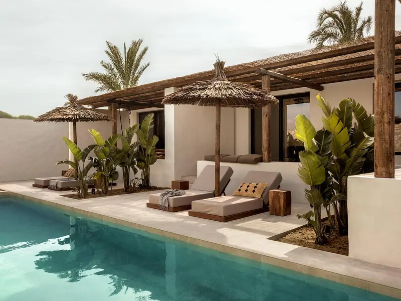 Transats et parasols ombragent une piscine bordée de végétation tropicale.