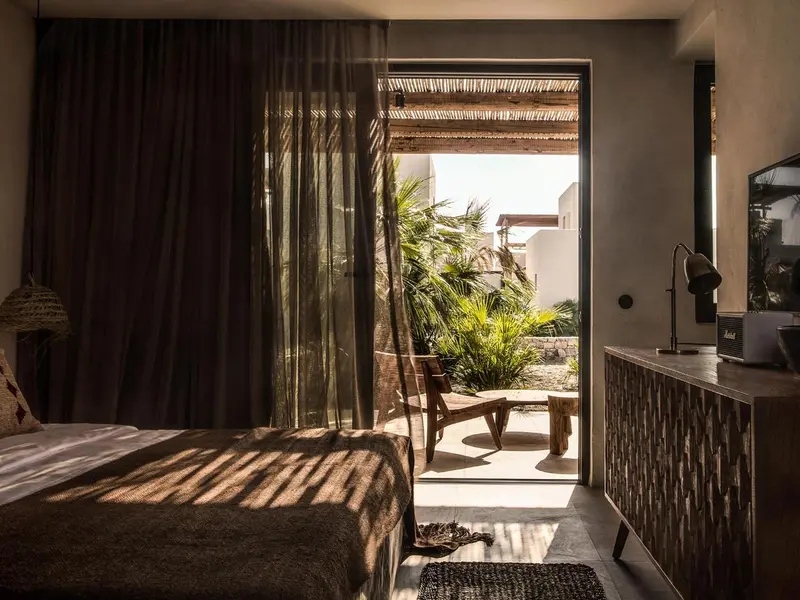 Une chambre lumineuse s'ouvre sur une terrasse ombragée.