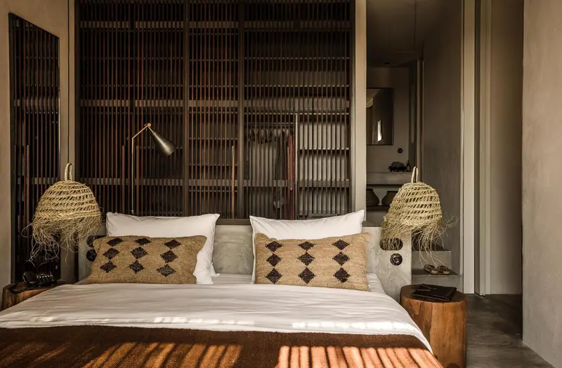 Une chambre lumineuse avec un grand lit et des luminaires en fibres naturelles.