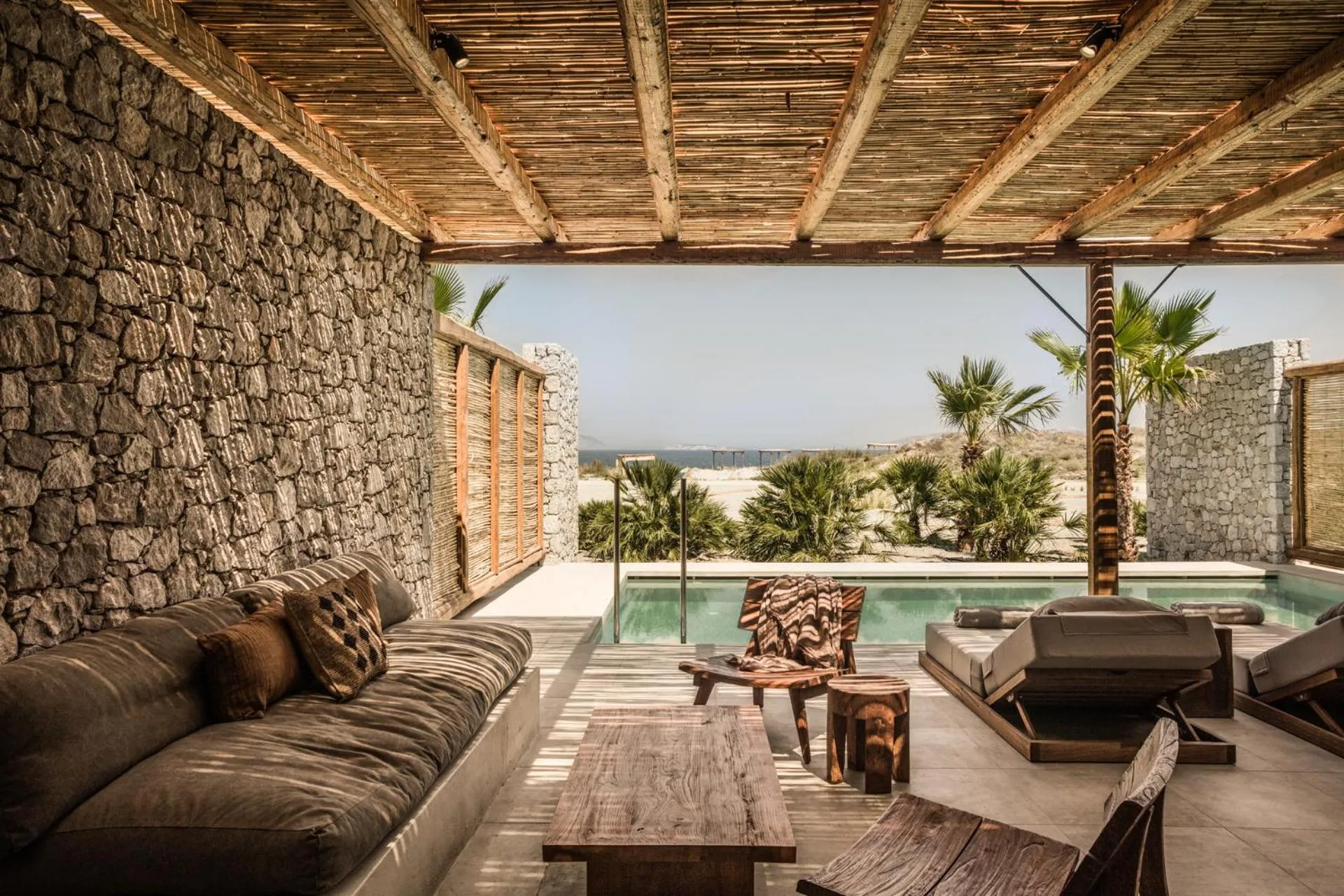 Espace de détente extérieur avec canapés et petite piscine face à la mer.