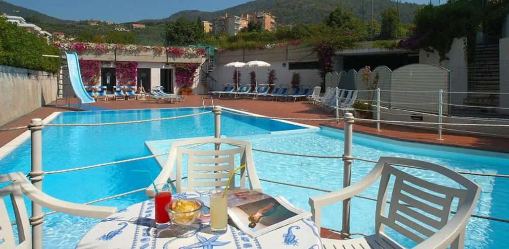 Une piscine avec des transats et une table basse décorée de boissons et de collations.