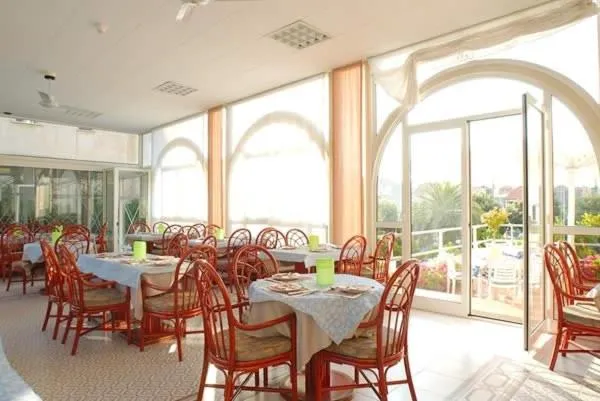 Une salle lumineuse avec des tables dressées pour un repas.
