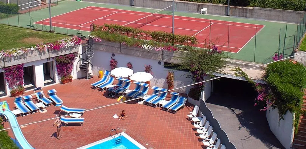 Terrasse avec transats et piscine au bord d'un court de tennis.
