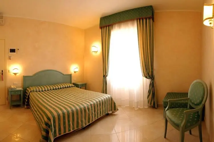 Une chambre lumineuse avec un lit recouvert d'une couette rayée et une chaise.