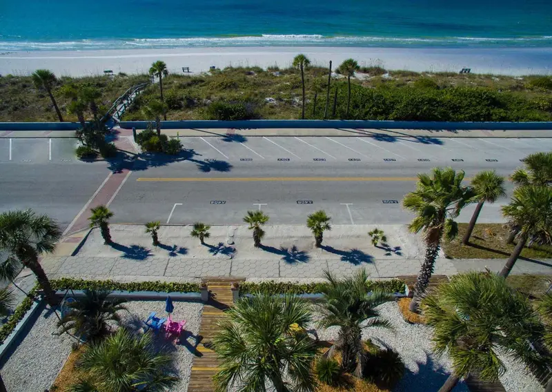 Vue aérienne d'un parking bordé de palmiers et d'une plage.