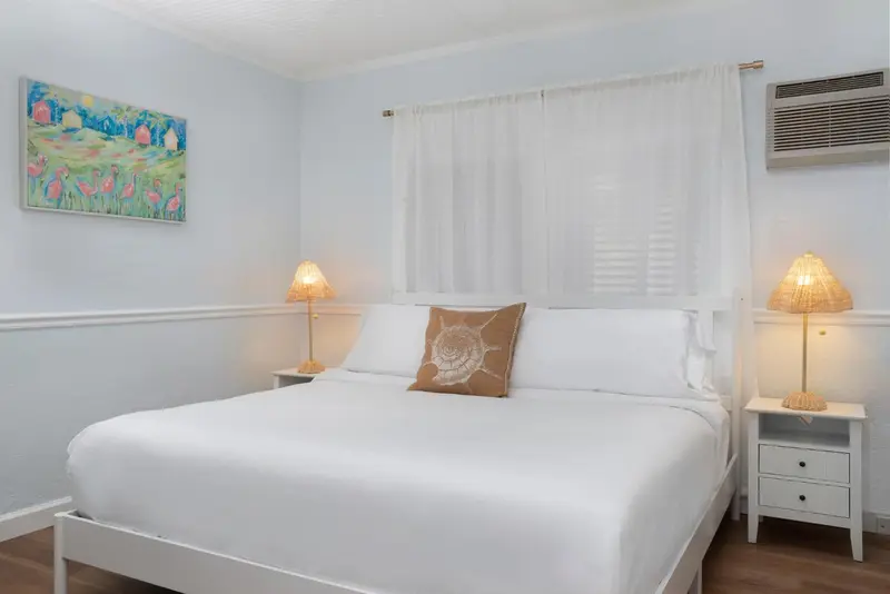 Une chambre lumineuse avec un lit blanc et des lampes de chevet.
