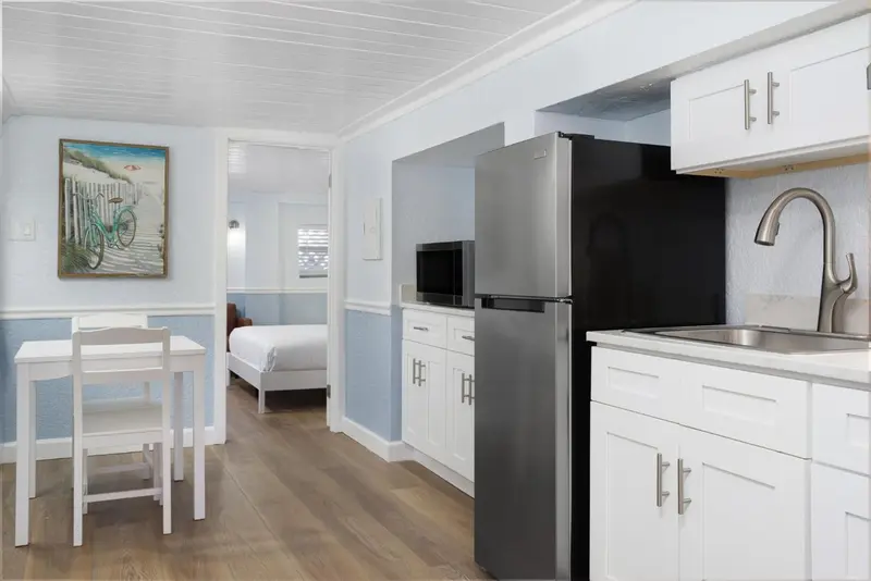 Une kitchenette lumineuse s'ouvre sur un espace de vie avec un lit.