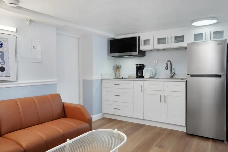 Un espace de vie lumineux avec un canapé et une kitchenette équipée.