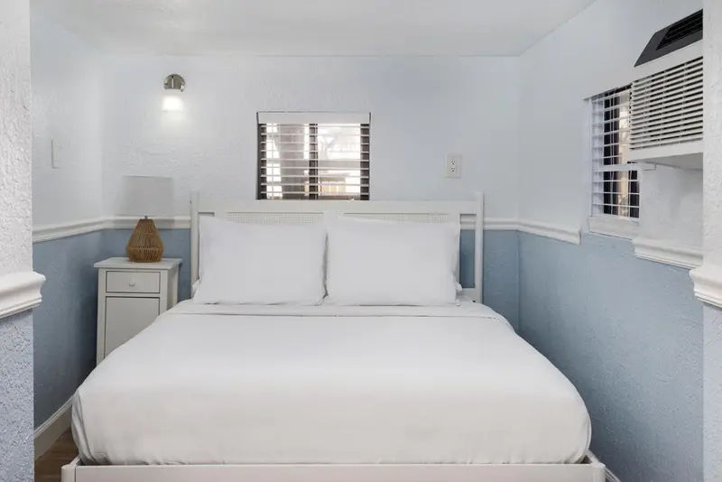Une chambre lumineuse avec un lit double et une fenêtre.