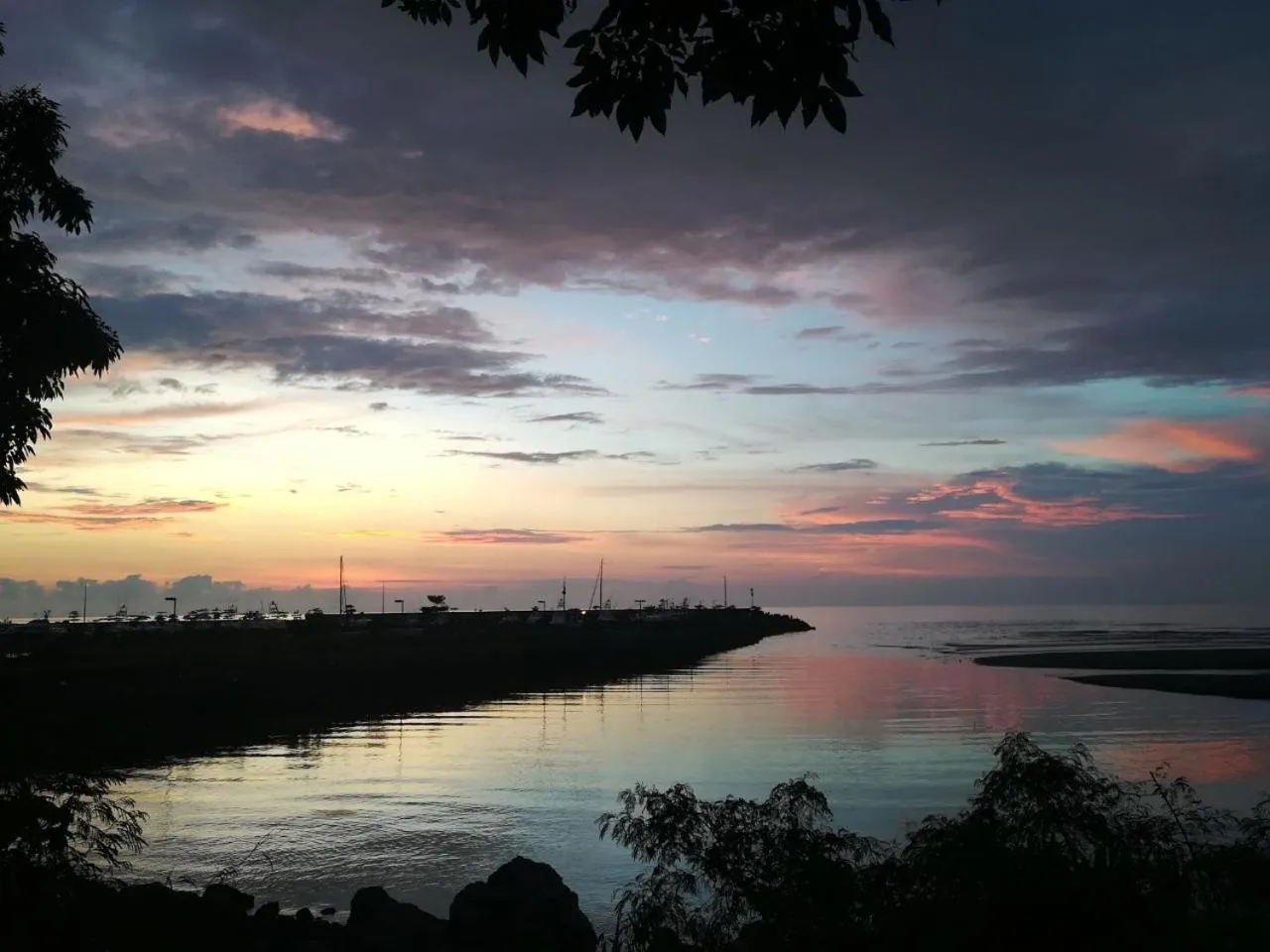 Coucher de soleil sur la mer avec une jetée au premier plan.
