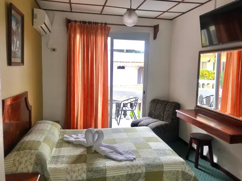 Une chambre lumineuse avec un lit recouvert d'une courtepointe et un coin salon.