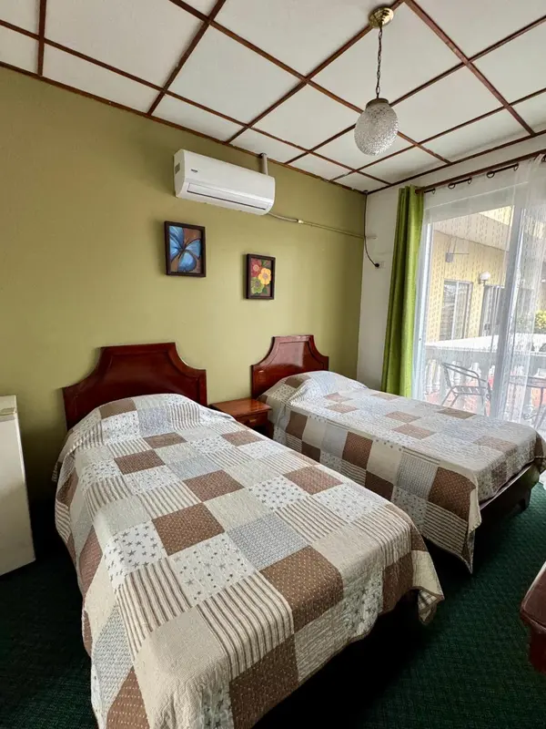 Une chambre avec deux lits simples et une climatisation murale.