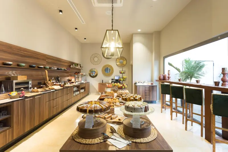 Un buffet propose une variété de pâtisseries et de plats dans une salle lumineuse.